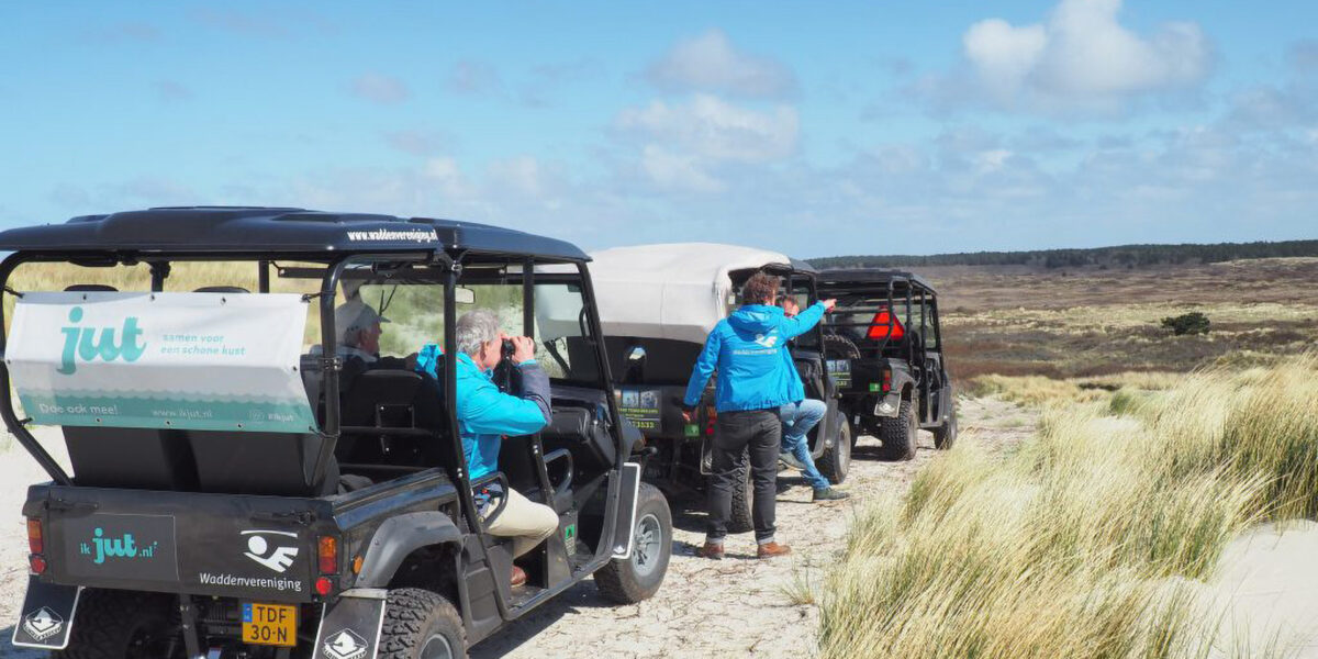 Man kijkt met een verrekijker vanuit een van de quads van EcoSafari de natuur van Terschelling in.